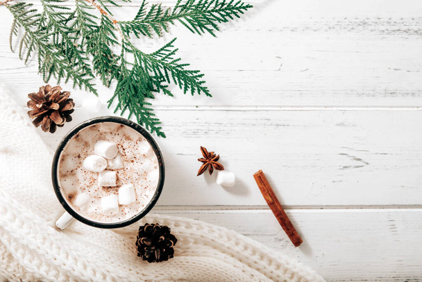 hot chocolate,  cocoa mug with marshmallows, white sweater, fir branches , cones, cinnamon sticks, star anise on a white wooden background, hot winter drink, place for inscription - Φωτογραφία, εικόνα