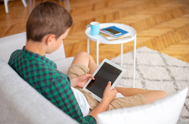 Nastolatek trzymający cyfrowy tablet z pustym ekranem, wnętrze domu - Zdjęcie, obraz