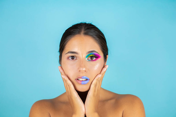 Portrait de beauté du modèle féminin avec un maquillage vif sur une moitié du visage et un visage propre sur l'autre partie sur fond bleu et lèvres bleues. - Photo, image