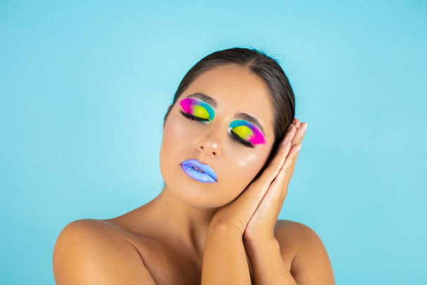 Beauty portrait of female model with vivid makeup on blue background and blue lips. - Photo, Image