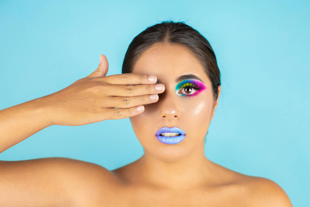 Beauty portrait of female model with vivid makeup on blue background and blue lips. - Foto, Imagen