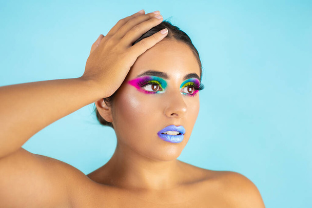 Beauty portret van vrouwelijke model met levendige make-up op blauwe achtergrond en blauwe lippen. - Foto, afbeelding
