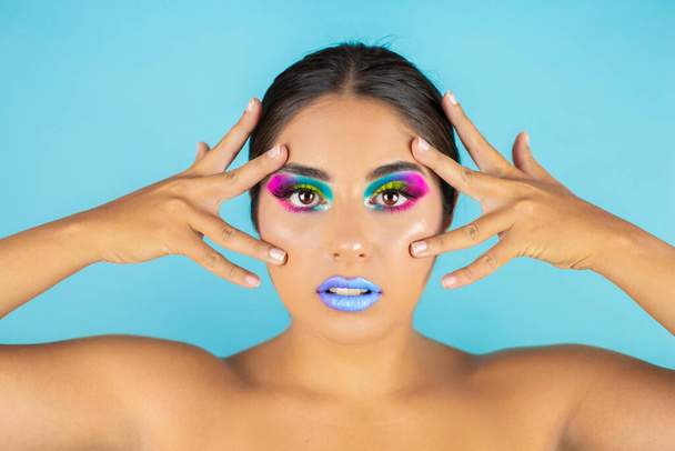 Beauty portrait of female model with vivid makeup on blue background and blue lips. - Φωτογραφία, εικόνα