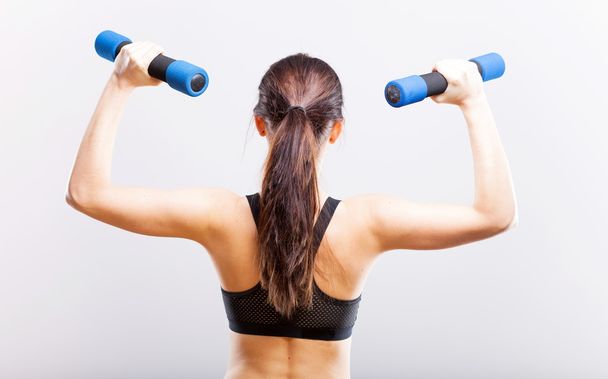 Fit woman during exercise with dumbbells, back view - Фото, зображення