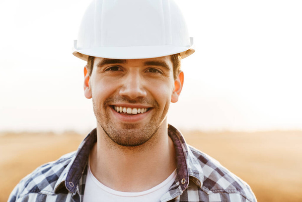 Close up of a smiling man in hardhat standing outdoors, industry, building, technology and people concept - Photo, image