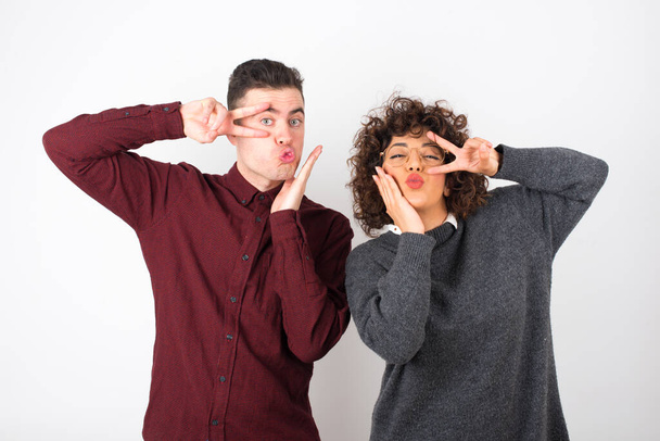  couple portant des vêtements décontractés montrant faire v-signes près des yeux - Photo, image