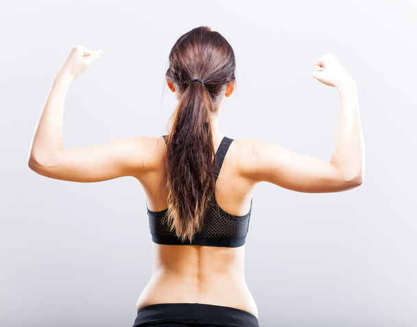 Fit woman flexing her biceps, back view - Фото, зображення
