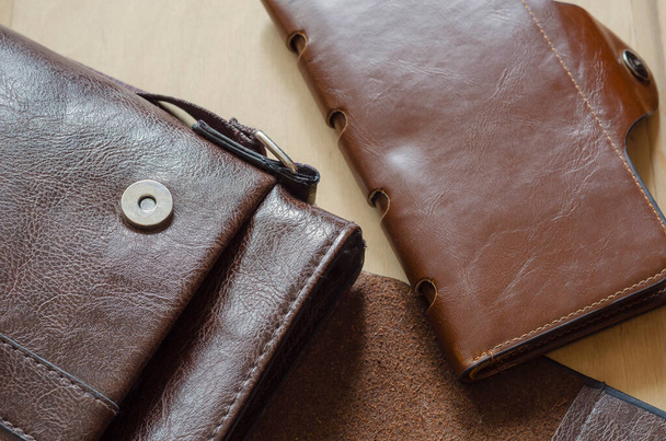 木製のテーブルの上に小さな革袋と財布。バッグと茶色の革財布を開きます。角度でトップビュー。選択的焦点. - 写真・画像