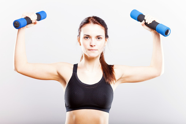 Young fit woman training with dumbbells - Foto, afbeelding