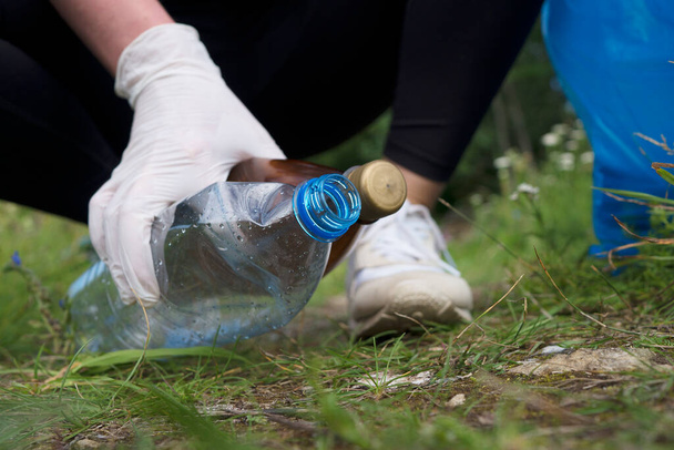 Volunteer collecting bottles in the forest. Environment pollution concept. - Foto, immagini
