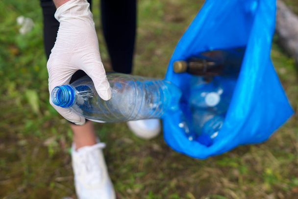 Volunteer collecting bottles in the forest. Environment pollution concept. - Foto, imagen