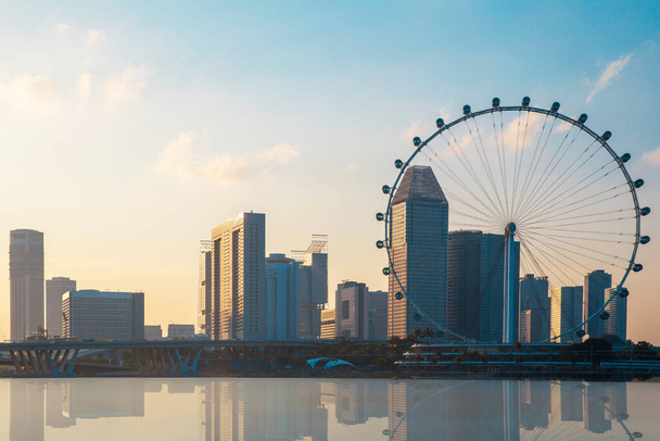 Άποψη του τροχού Giant Ferris και το φόντο του κτιρίου της πόλης της Σιγκαπούρης στο ηλιοβασίλεμα - Φωτογραφία, εικόνα