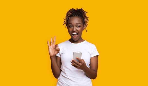 Emocionální černošky dívka s chytrým telefonem ukazuje v pořádku - Fotografie, Obrázek