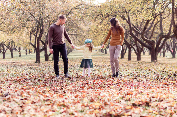 Mam, pap en hun dochtertje lopen in het herfstpark. Horizontale foto - Foto, afbeelding