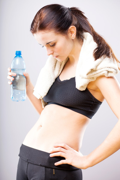 Woman looking at her flat stomach with water bottle - Photo, image