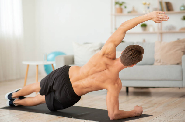 Мужчина занимается спортом дома онлайн и показывает мускулистую спину. - Фото, изображение