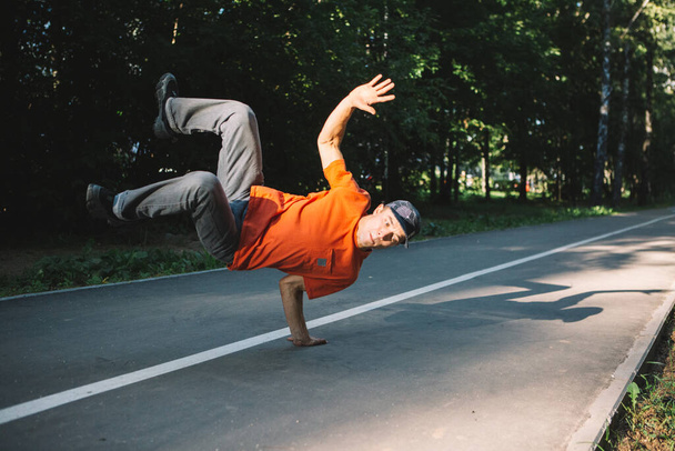 Cool young guy dancing breakdance on the road in the park in summertime. Breakdancing school poster - Foto, imagen