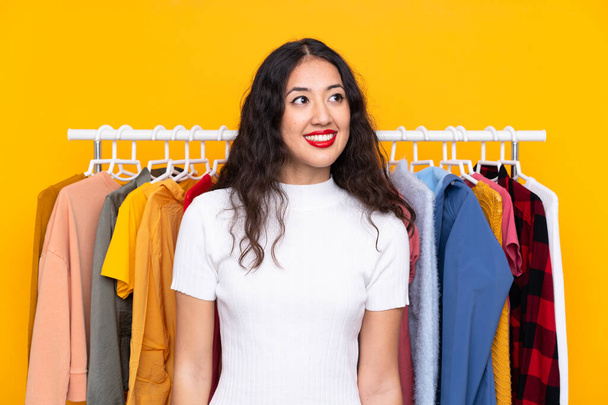 Mujer de raza mixta en una tienda de ropa riendo y mirando hacia arriba - Foto, Imagen