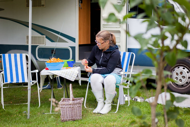 Vrouw die buiten een camper zit met veel cantharellen op tafel - Foto, afbeelding