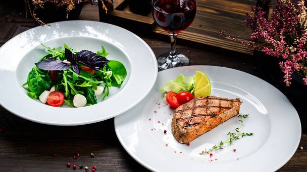 two plates of steak and salad on the table, lunch in the restaurant, grilled tuna - Φωτογραφία, εικόνα