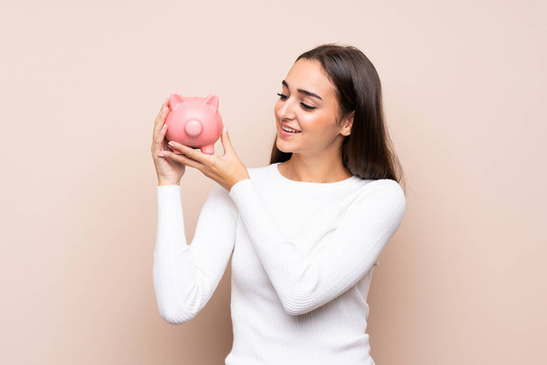 Young woman over isolated background holding a big piggybank - Photo, Image