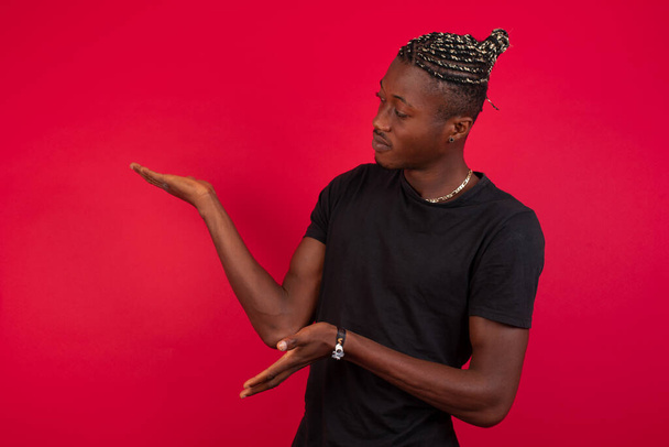 handsome caucasian young african american man  pointing aside with both hands showing something strange and saying: I don't know what is this. Standing against  background. Advertisement concept. - Фото, зображення
