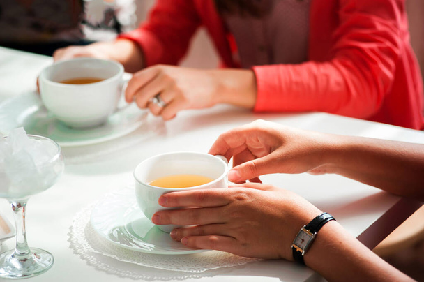 Mãos femininas segurando uma xícara branca de chá de pé - Foto, Imagem