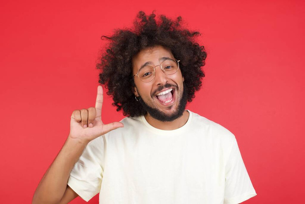 Junger Mann mit Afro-Haaren hat Idee gegen rote Wand    - Foto, Bild