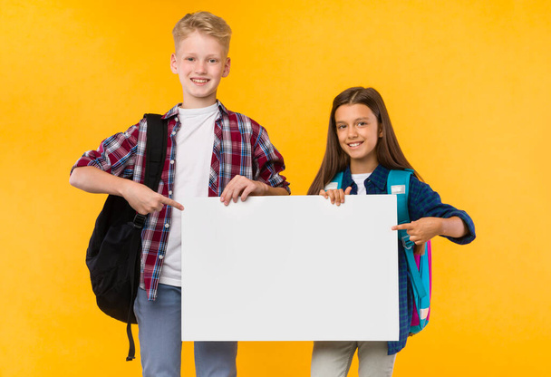 Excited girl and boy holding white paper for promo - Fotó, kép