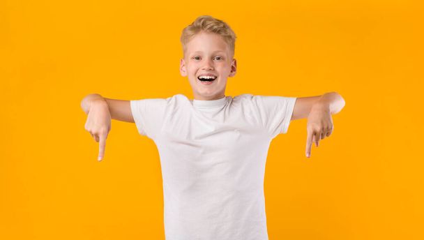 Ευτυχισμένο αγόρι δείχνει τα δάχτυλα κάτω στο χώρο αντιγραφής - Φωτογραφία, εικόνα