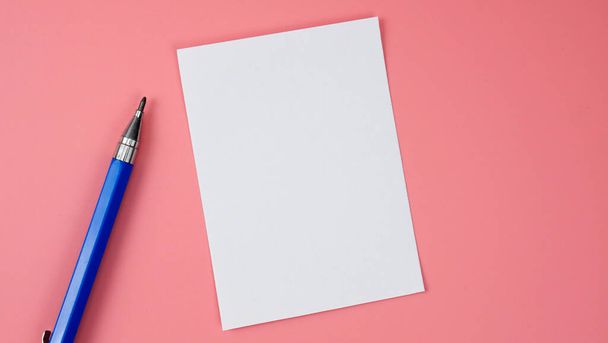 Lápiz azul y bloc de notas sobre fondo rosa, vista superior en blanco para el diseño. - Foto, Imagen