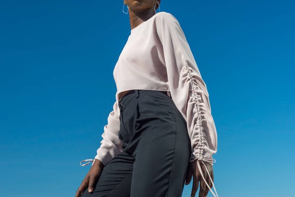 Closeup portrait fashionable dark skinned girl, African girl in a blouse and business pants, posing. Against the background of blue sky. Fashionable black girl, blacks fashion. young Nigerian girl, young African girl, twenty five years old, posing in - Fotoğraf, Görsel