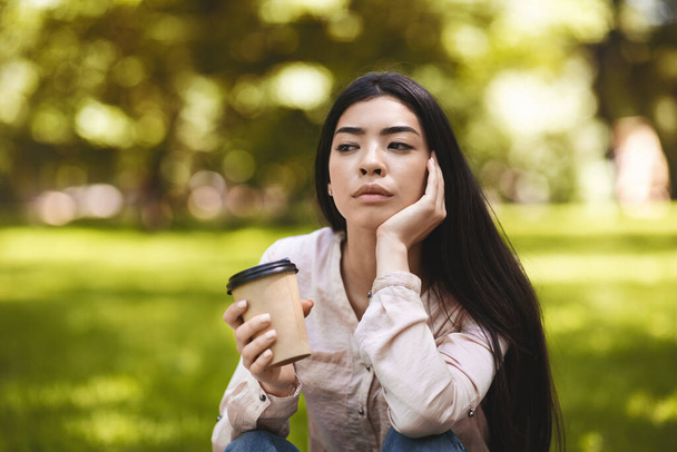 Кава на відкритому повітрі. Pensive азіатська дівчина насолоджуючись takingaway напій в Park
 - Фото, зображення