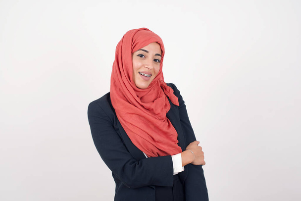 Mooie moslim vrouw draagt zwarte blazer en hijab tijdens leuk gesprek met iemand. - Foto, afbeelding