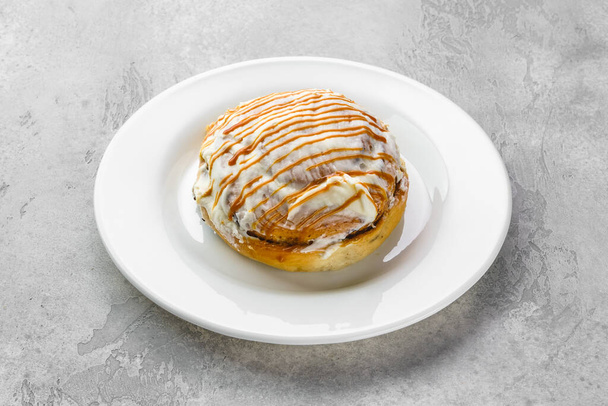 Fresh cinnamon bun with sugar icing and caramel - Фото, изображение