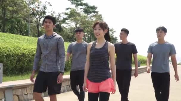 ομάδα πέντε νεαρών ασιατών που περπατούν μιλώντας χαλαρωτικά σε εξωτερικούς χώρους μετά την άσκηση - Πλάνα, βίντεο