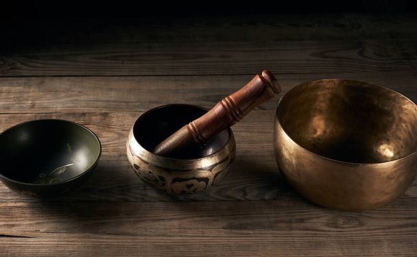Bol tibétain en cuivre chantant avec un battant en bois sur une table en bois marron, objets de méditation et médecine alternative - Photo, image