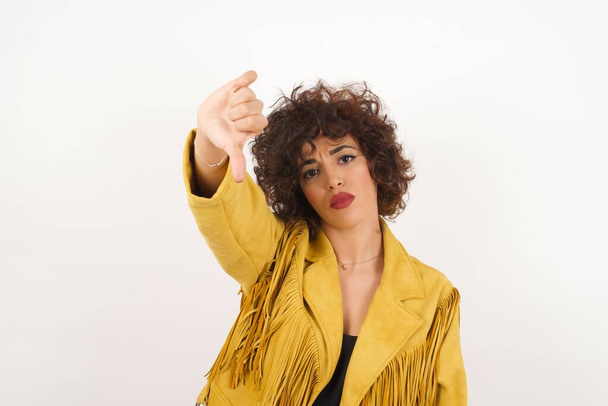 Mulher bonita em jaqueta de camurça com polegar para baixo estúdio tiro - Foto, Imagem