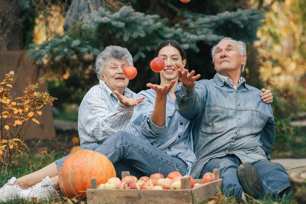 Family sitting in a garden with apples and pumpkin - Foto, Imagem