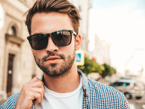 Portrait of handsome confident stylish hipster lambersexual model.Man dressed in white T-shirt. Fashion male posing on the street background - 写真・画像