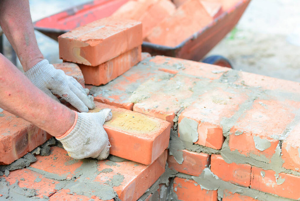 A mason person is bricklaying a wall of a new house from red bri - Photo, Image