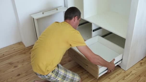 mężczyzna stolarz montaż mebli szafy i montaż drewniane nowe szuflady. - Materiał filmowy, wideo