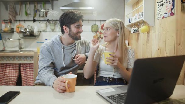Bella coppia che parla e ride durante la colazione in cucina - Foto, immagini