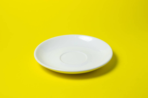 Valkoinen lautanen keltaisella pohjalla. Tyhjä vaaleanpunainen lautanen makaa keltaisella pinnalla - Valokuva, kuva