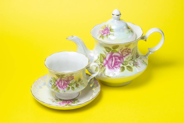 黄色を基調としたお茶。カップとソーサーとティーポットの隣にあります。花飾り茶セット - 写真・画像