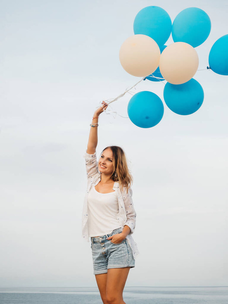 Young woman holding blue and white helium balloons - Foto, afbeelding