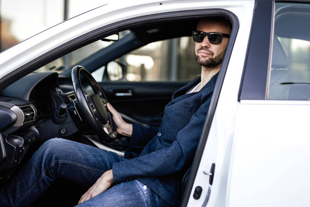 Un hombre de negocios adulto está sentado en su coche nuevo - Foto, Imagen