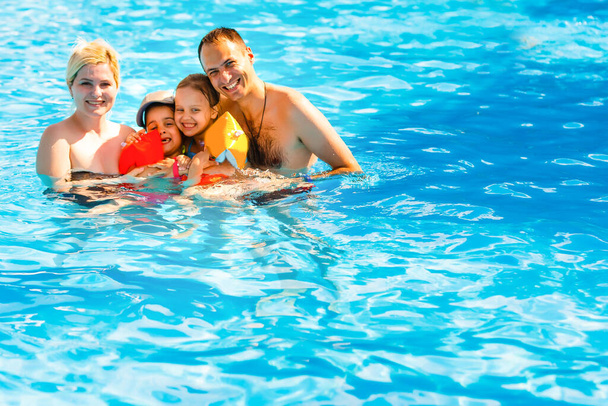 Νεαρή οικογένεια, γονείς με παιδιά, στην πισίνα - Φωτογραφία, εικόνα
