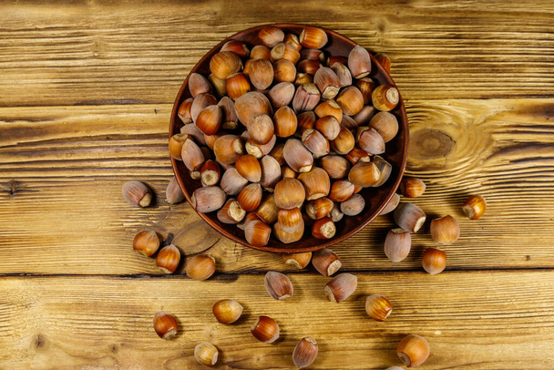 Hazelnuts in ceramic plate on a wooden table. Top view - Foto, Imagem