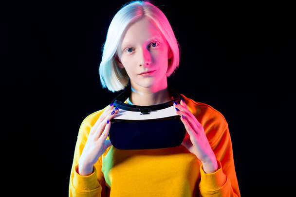 young albino wearing virtual reality device on her neck over black background. - Foto, immagini